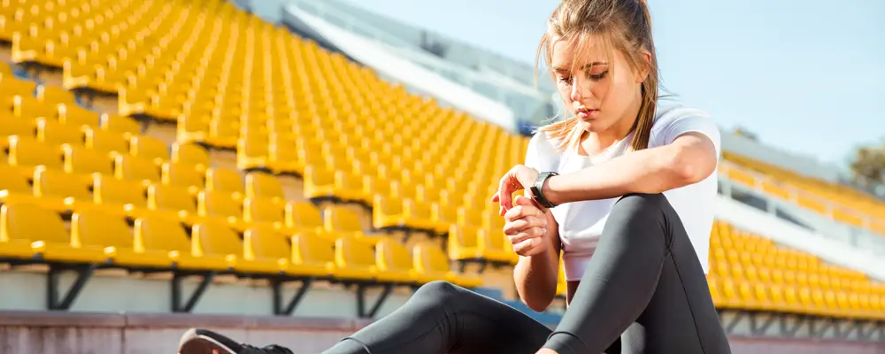 Portrait of a young woman resting and looking on wrist watch at stadium