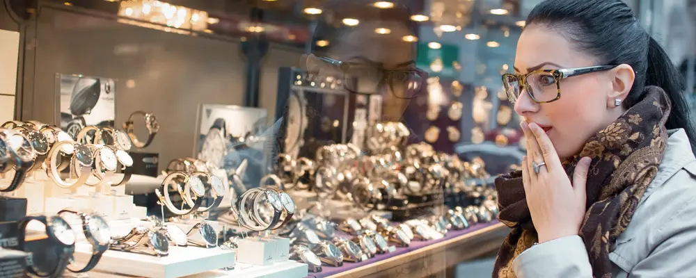 Astonished woman looking to showcase or shop window. Surprised shopping girl chooses jewelry in store