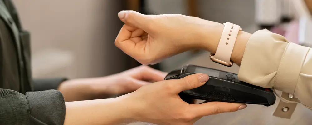 Hand of young contemporary female customer with smartwatch keeping her wrist over pos terminal during contactless payment