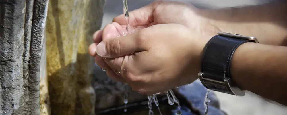 Person's hands with watch on flowing water